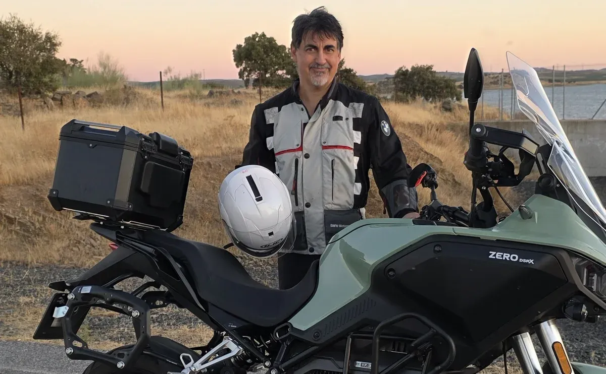 Tomás de la Hera junto a una moto eléctrica al atardecer